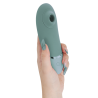Vista frontal de Womanizer Next verde claro en la mano