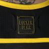 Detalle del distintivo Locker Gear sobre tejido negro perforado con ribete amarillo