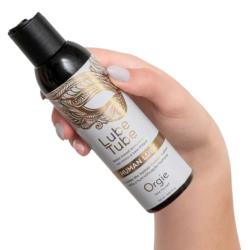 Mano sosteniendo un frasco de Orgie Human Lube con el tapón dosificador visible