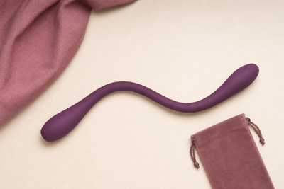 Dildo morado flexible de dos extremos junto a una bolsa de tela