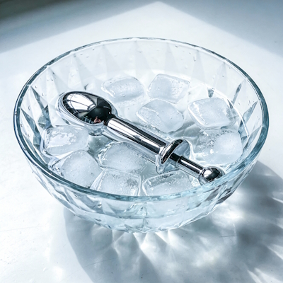 Juguete sexual de metal dentro de un bol con agua fría y hielo para juego de temperatura